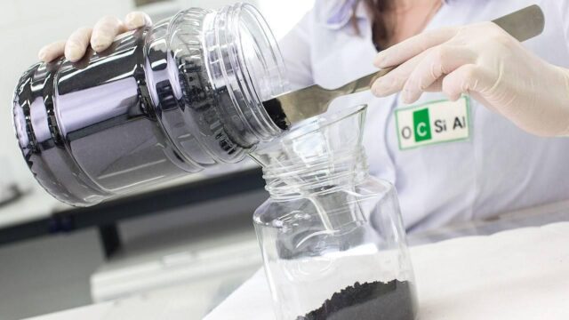 A lab worker is pouring graphene from a glass into another