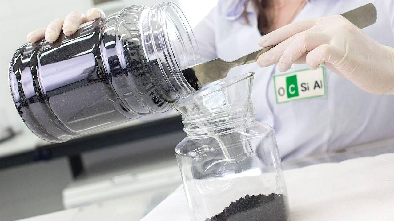 A lab worker is pouring graphene from a glass into another
