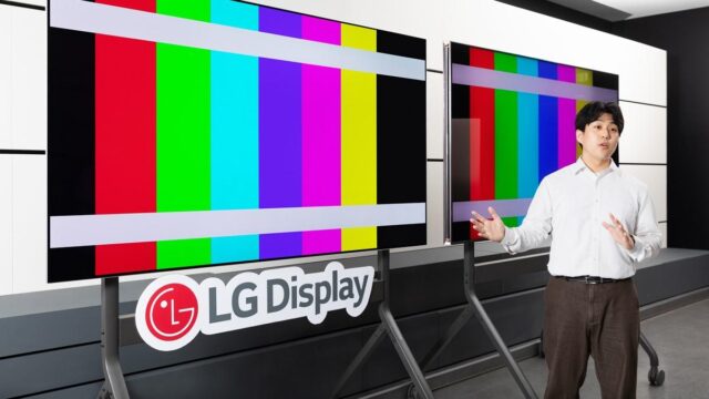 An LG employee in front of two OLED screens